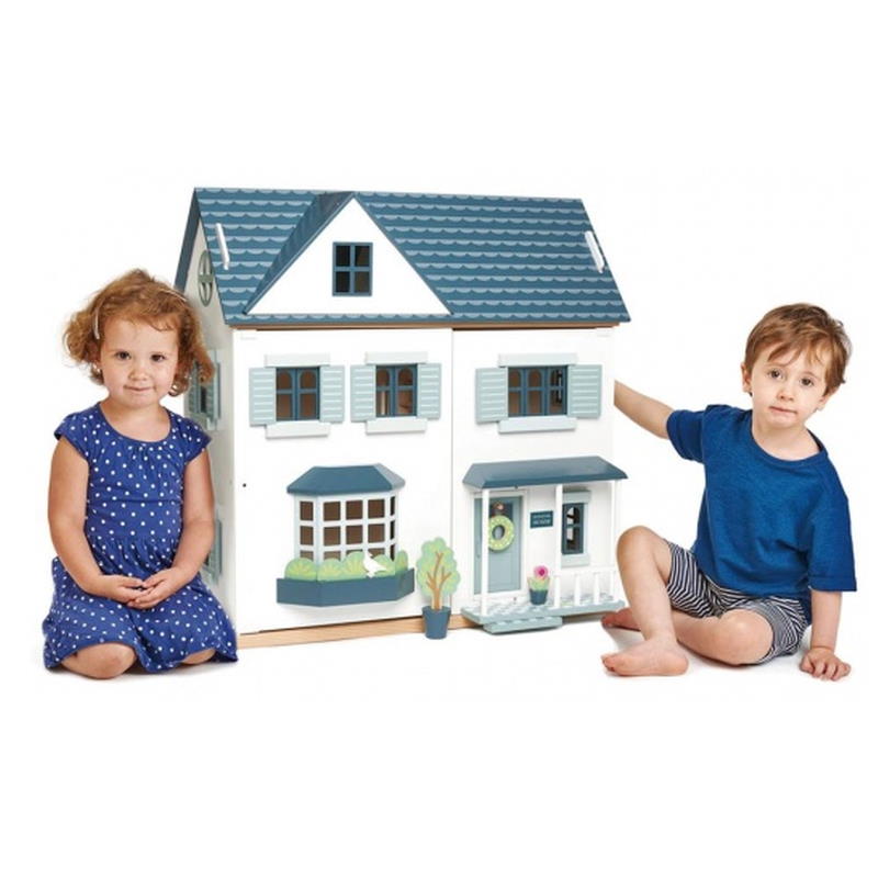 Mädchen und Junge spielen mit einem Puppenhaus aus Holz