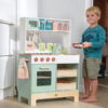 Junge steht neben Spielküche aus Holz in mintgrün